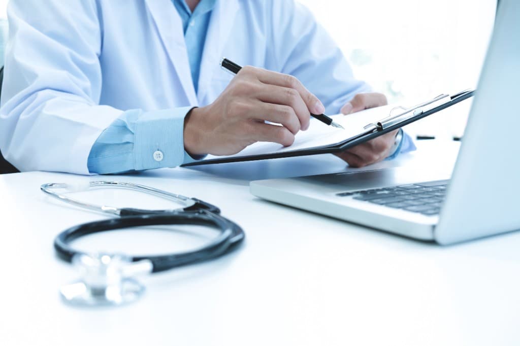 Healthcare professional managing medical billing paperwork and records at a desk