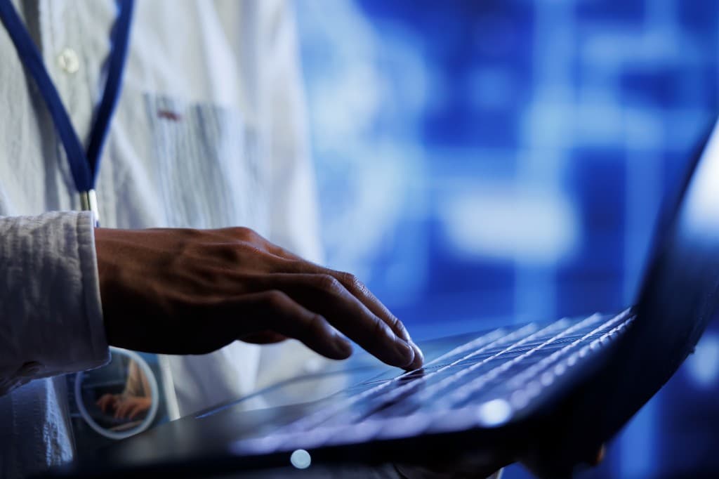 Healthcare professional working on medical coding and documentation at a laptop